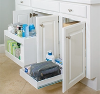White bathroom cabinets with towels and bottles.