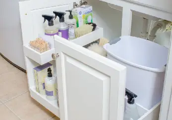 White cabinets drawers with trashcan in the bathroom.