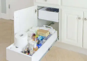 White bathroom cabinets full of items.