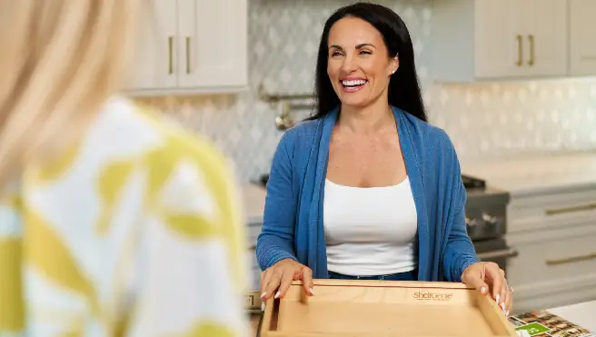 Woman smiling holding a cutting board with ShelfGenie logo.