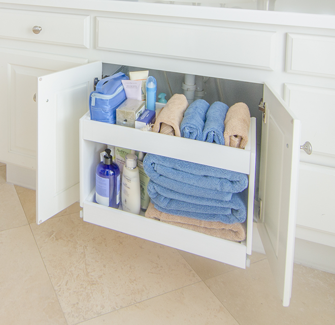 White bathroom shelves with towels and bottles.