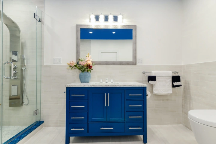 Bright blue freestanding vanity unit with a white tiled and painted wall