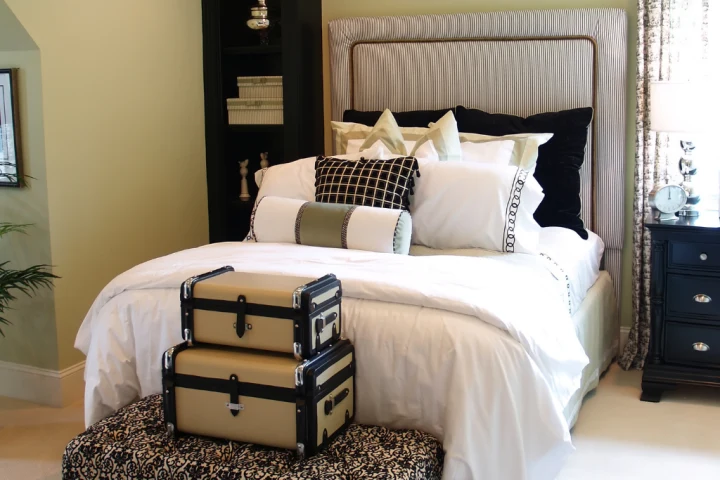 Simple patterns and neutral tones paired with storage-purposed furniture make a small guest bedroom feel even larger.