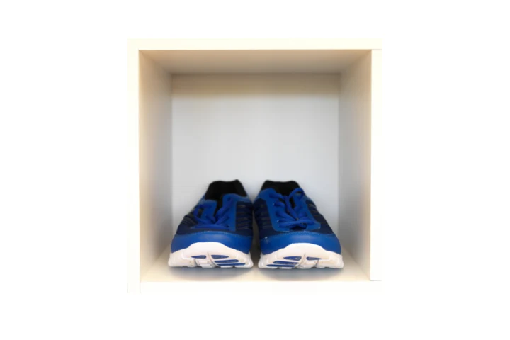 A cubbyhole with a pair of blue sneakers in it.