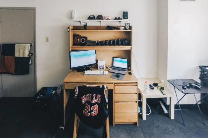 A desk with a computer and a guitar on it.