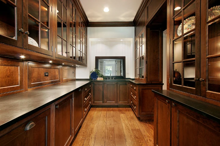 a kitchen with dark wood cabinets and glass doors.