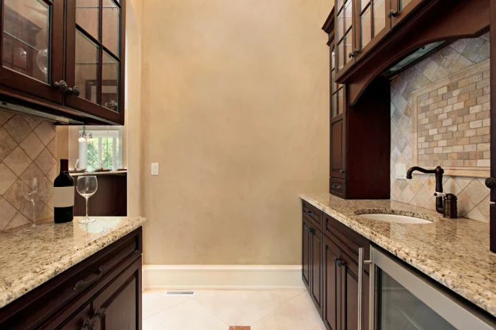 A kitchen with granite counter tops and a wine glass.