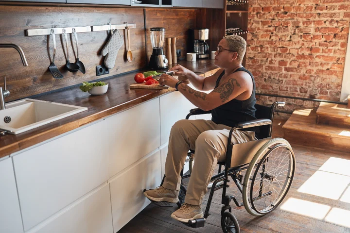 A person in a wheelchair cooking in a kitchen.