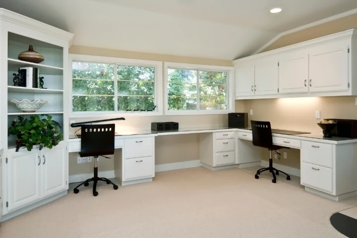 A room with white cabinets and a desk.