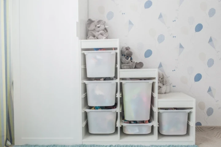 A shelf with plastic bins and stuffed animals.