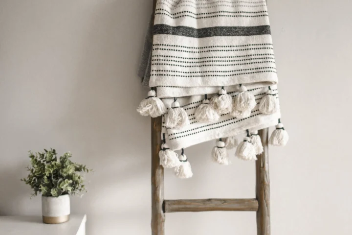 A white and black striped blanket on a wooden ladder.
