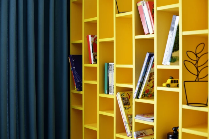 A yellow bookcase with books on it