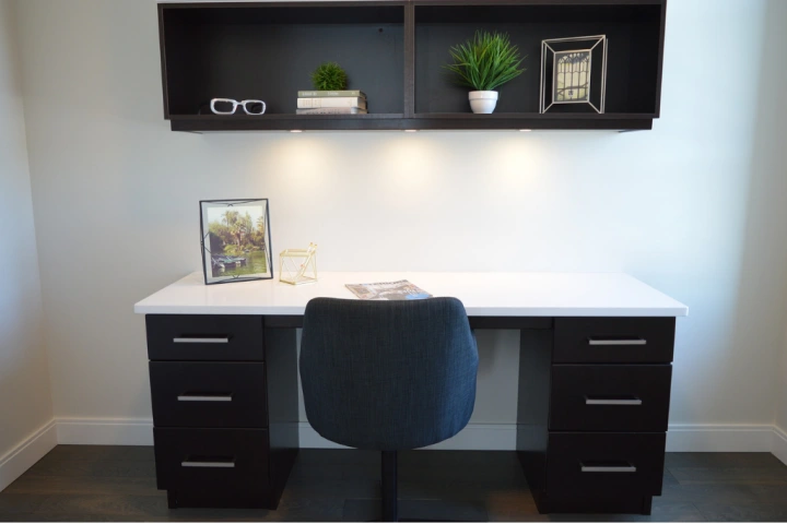 A black and white desk with matching wall shelving unit for home office storage ideas.