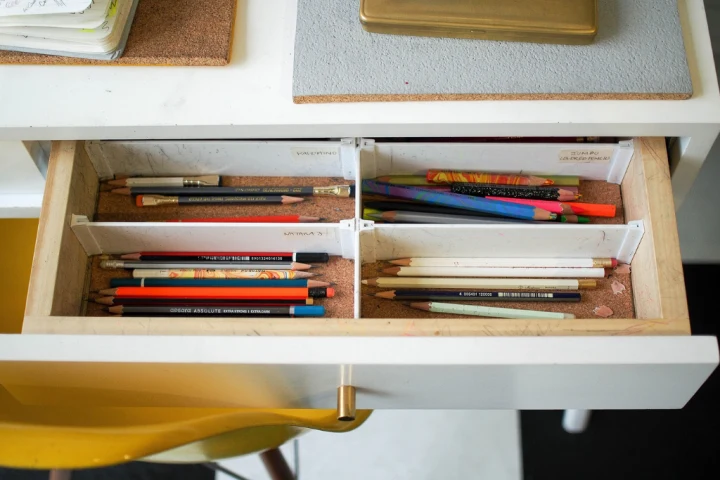 Open drawers with dividers to organize writing and drawing tools.