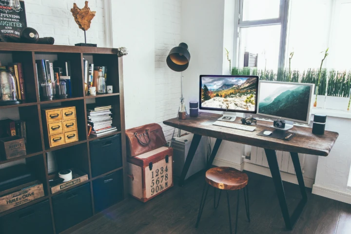 Home office with a wooden desk and bookcase with boxes and ornaments.