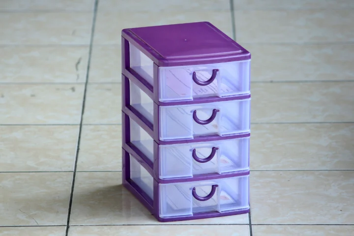 Purple transparent plastic tiered drawers on a tiled floor.