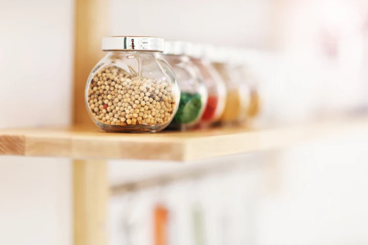 A group of jars of spices on a shelf.