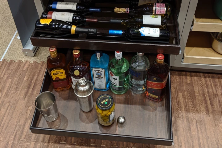 A shelf with bottles of alcohol and a metal shaker.