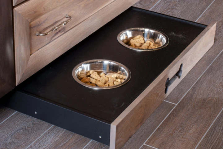 Two silver dog bowls embedded securely in a black and hickory wood toe kick drawer.