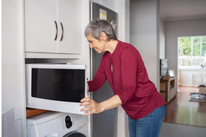 Old woman using microwave.