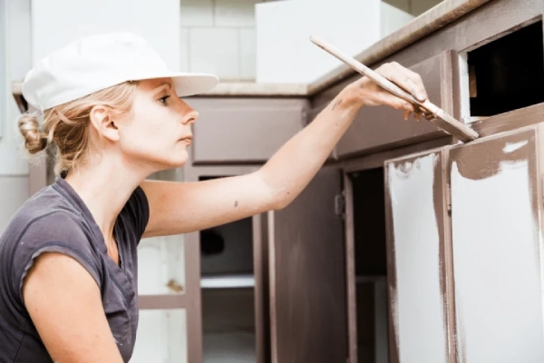 Woman painting kitchen cabinet.